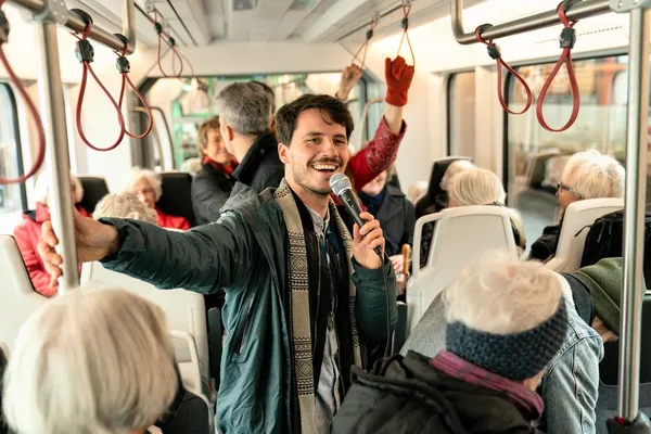 Noa Kjærsgaard Hansen med mikrofon blandt passagerer i letbanen